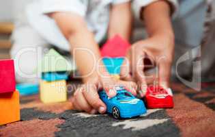 Closeup hands playing with fun toys, cars and building blocks in a home living room. Parent bonding, having fun and enjoying family time with a playful, small and little child during childhood fun