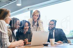 The team has got their full attention on the screen. a group of focussed businesspeople browsing on a laptop together in the office at work during the day.