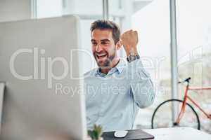 Guess who just bagged another deal. a handsome young businessman doing a fist pump while working on a computer in an office.