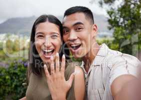 Engagement, ring and celebration with a young couple announcing their happy news and special occasion. Closeup portrait of a man and woman taking a selfie after getting engaged to be married outside