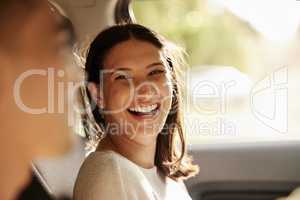 Happy, cheerful and laughing woman enjoying a road trip, holiday or vacation with her boyfriend in the car. Latino woman having fun in a vehicle while on a journey to a romantic destination
