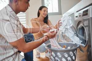 Chores, couple laundry and washing machine during routine washing, cleaning and housework at home. Man and woman bonding, cleaning and maintaining personal hygiene with household appliance and dryer