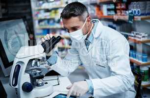 The microscope reveals all. a mature man using a microscope and digital tablet while conducting pharmaceutical research.