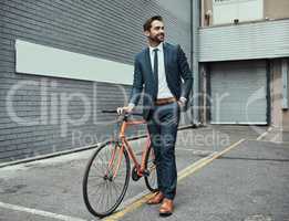 Getting to work on time and in style. a handsome young businessman standing alongside his bike outdoors.