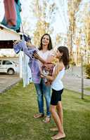 Getting involved to help get the laundry done. Portrait of a mother and daughter hanging up laundry together outside.