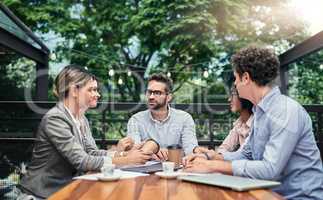 Meeting with a change of scenery. a group of business colleagues having a meeting outdoors at a cafe.