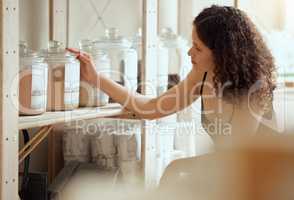 Zero waste shopping or choosing organic and vegan products or spices on a shelf of a shop. A young woman customer or consumer buying condiments in jars at a food store on a weekend