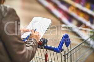 Making life easier with a shopping list. a woman shopping with a list in a grocery store.