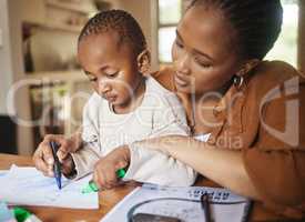 African mother and small child drawing together at a desk at home. Caring, working woman making family time to play with kid. Fun and educational activities for loving mom and artistic young son.