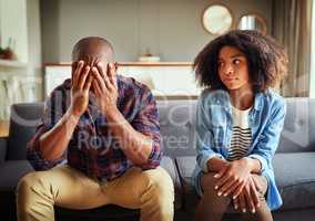 I hope this day will get better later. a stressed out young couple seated on a couch together while contemplating at home during the day.