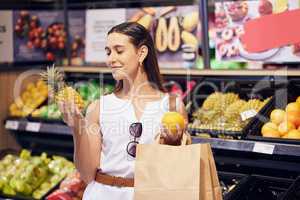 Shopping, holding and looking at fruit at shop, buying healthy food and examining items at a grocery store. Woman deciding, choosing and picking ripe, fresh and delicious produce at a market