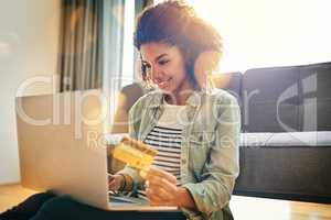 This is way better than standing in a queue. a cheerful young woman doing online shopping on her laptop while being seated on the floor at home.