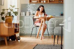 Diet, healthy life and food of a hygienic female sitting alone looking up nutrition value of an apple on a phone. Young woman at home living a clean, balanced and organic lifestyle in the kitchen.