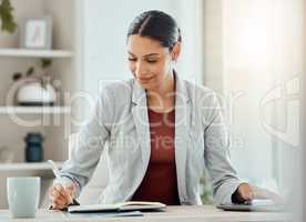 Female manager, boss or CEO writing notes in her diary, marking appointments in her calendar or organizing a schedule. Corporate professional feeling motivated and working at her desk in the office