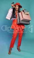 Shopping with credit card, holding bags and enjoying retail therapy spree while standing against a blue studio background. Stylish, elegant and beautiful woman buying items and fashion clothes