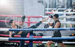 Fit, active and healthy kickboxing athletes exercise training together in boxing ring in modern sports gym. Sporty and strong woman workout with her fitness coach trainer together in fighting studio