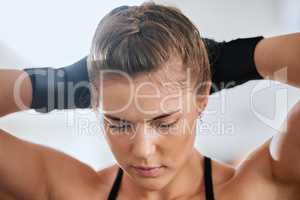 Face of a young female boxer getting ready to train in the gym for a boxing match. Sporty, active and healthy athlete tying her hair to exercise. Motivated woman doing a fitness workout.