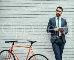 Everything he does is with convenience in mind. a handsome young businessman using a digital tablet while standing alongside his bike outdoors.