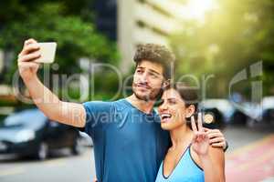 Stay tuned for our big transformation. a sporty young couple taking a selfie together outdoors.