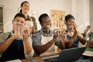 Clapping, cheering and excited fashion design team celebrate at workplace. Coworkers welcome and support employee promotion. Diverse group of happy, smiling creatives celebrating in a workshop.