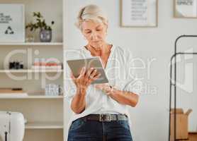 Senior businesswoman, manager or designer reply, responding or sending notification of online orders from handheld tablet. Old clothing producer or business owner serious searching the web in studio.