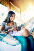 Smile for mommy. a cheerful young mother relaxing on a hammock with her infant son outside at home during the day.