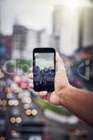 There is beauty amidst the chaos of the city. an unrecognizable man taking a picture with a cellphone in the city.