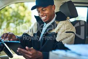 His deliveries are all digitally organized. a courier using a digital tablet while sitting in a delivery van.