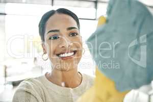 Cleaning, chores and cleaner wiping windows with a soft cloth while wearing gloves in office. Smiling, young and female maid doing hygiene housekeeping. Beautiful lady keeping her home clean.