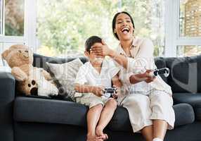 Mother and son playing video games, having fun and enjoying quality time together. Cheerful, bonding and carefree child and parent using a gaming console or interactive modern technology