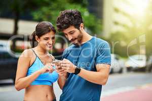 Browsing online for new exercises to incorporate in their fitness routine. a sporty young couple using a cellphone while exercising outdoors.