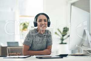 Relaxed, satisfied businesswoman listening to music in headphones while sitting alone in an office. Female office worker enjoying a podcast or songs during a break in a corporate company