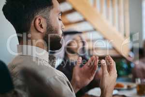 Muslim, praying and religion while sitting with family and say a dua or prayer before breaking fast during the holy month of Ramadan. Religious man lifting his hands to pray during eid or iftar meal