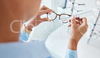 Optician or optometrist hands measuring and preparing pair of glasses and frame with optic ruler tool. Eye doctor or ophthalmologist determines visual or vision lens size using special eyewear scale.