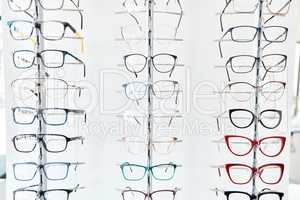 Glasses, optometrist and shelf with new, trendy and colorful spectacles in a display window in the retail and eye care industry. Window shopping eyewear on showcase in an optometry or optical store