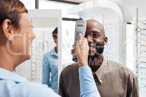 Eye exam, eyewear and an optometrist checking happy young male eyes with optic medical equipment. African man getting his eyesight checked by a tonometer. Smiling guy getting new spectacles.