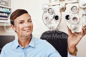 Portrait of professional optometrist, confident and happy in an optometry office preparing equipment for eye checks. Caucasian female health and ophthalmology expert ready to test a patient