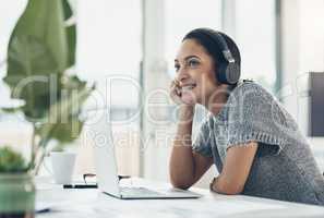 Happy, smiling business woman day dreaming of success at her office desk in a modern office. Female office worker enjoying a podcast or songs during a break in a corporate company over copy space.