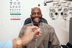 Black man having his eyes tested at an optometrist. Smiling African American male consulting with an opthamologist, having a vision and eye care checkup. Guy testing for glaucoma or myopia