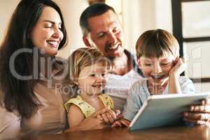 The internet is filled with fun family friendly activities. a young family of four using a digital tablet together at home.