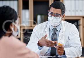 Medical appointment or doctor consulting a patient during the covid pandemic from his office. Male GP helping a sick client by giving her tablets, medication or medicine and wearing a face mask