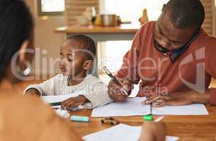 Busy and multitasking father talking on a call while taking care of his child at home. African american entrepreneur or freelancer analyzing paperwork with his wife caring for his busy little son