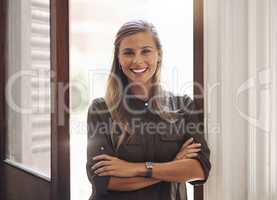 Portrait of a beautiful, standing and smiling successful lawyer in a her modern law firm. Young, happy and professional female caucasian leader inspiring the young generation in her office.