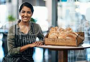 Portrait of a female restaurant waiter, baker or coffee shop retail manager with fresh bread for breakfast. Smiling, happy and young woman bakery worker ready to welcome a customer and work in a cafe