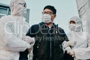 Asian man breaking covid regulation getting taken away or arrested by healthcare workers wearing hazmat protective suits. Male removed for not following the rules or restrictions of the pandemic.