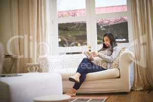 Reading calms her into complete relaxation. a pregnant woman reading a book at home.