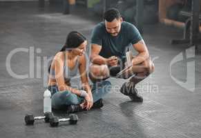 Personal trainer, coach or fitness instructor helping an active and fit woman in the gym. Young female athlete sitting down and managing her workout routine or schedule with her exercising partner