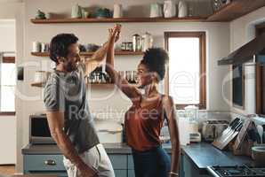 Happy, in love and dancing while an interracial couple have fun and enjoying time together in home kitchen. Husband and wife sharing a dance while being active and affectionate in loving relationship