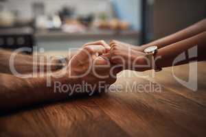 Couple holding hands in support, grief and healing together on a wooden table at home. Closeup of a caring partner in sorrow due to cancer and expressing feelings of compassion in a house