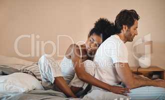 Sad, frustrated and unhappy man and woman hugging after a breakup in their bedroom. Upset, annoyed and depressed male getting support with his wife. Interracial couple cuddling to comfort husband.